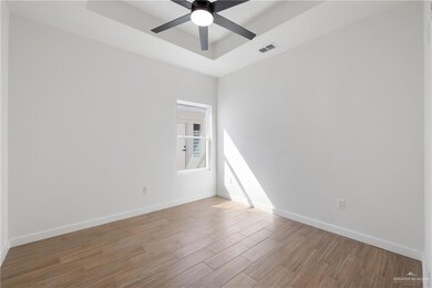 Empty room featuring a raised ceiling, wood finished floors, and ceiling fan