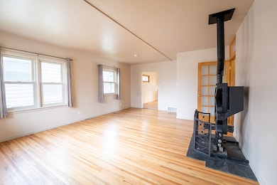 Unfurnished living room featuring light wood-style flooring and a wood stove