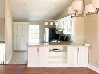 Kitchen with range, freestanding refrigerator, a chandelier, under cabinet range hood, and plenty of natural light