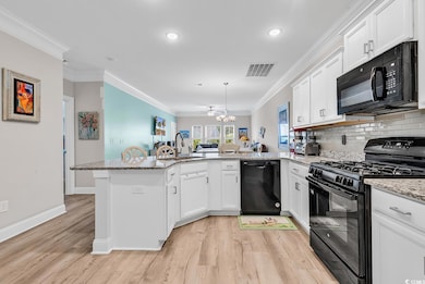 Kitchen featuring black appliances, a peninsula, a sink, white cabinetry, and ornamental molding