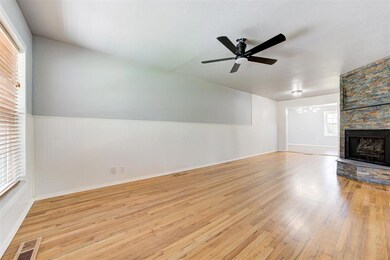 Unfurnished living room with wood finished floors, wainscoting, a fireplace, a ceiling fan, and a chandelier