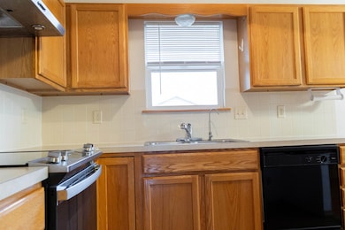 Kitchen featuring electric range, dishwasher, backsplash, under cabinet range hood, and light countertops