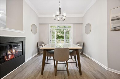 Dining room featuring wood finished floors, a chandelier, ornamental molding, and a glass covered fireplace