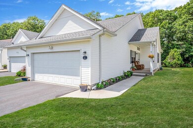 View of front of home with a garage, a shingled roof, driveway, a front lawn, and a porch