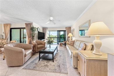Living area featuring ceiling fan, crown molding, light tile patterned floors, and a textured ceiling
