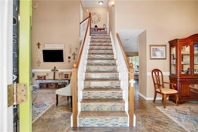 Staircase with a towering ceiling, wood finished floors, and baseboards