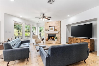Living area with light tile patterned floors, a stone fireplace, ceiling fan, and recessed lighting