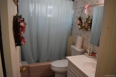 Bathroom with shower / bath combo, vanity, and wallpapered walls