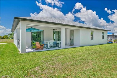 Rear view of property featuring a yard, ceiling fa