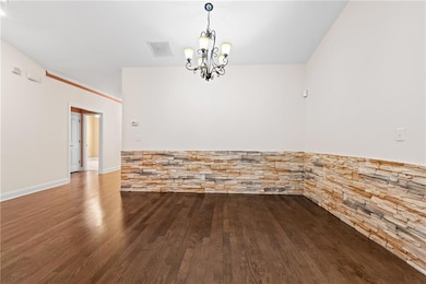 Empty room featuring wood finished floors and a chandelier