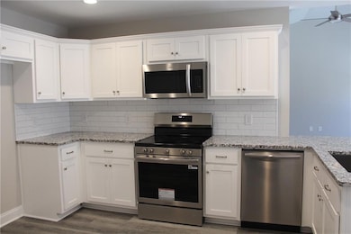 Kitchen featuring appliances with stainless steel finishes, white cabinets, and backsplash