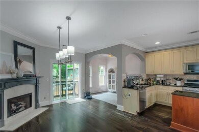 Kitchen with appliances with stainless steel finishes, cream cabinetry, dark countertops, dark wood-style floors, and crown molding