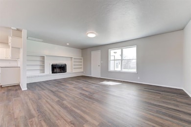 Unfurnished living room with a brick fireplace, ba
