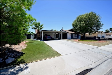 Ranch-style house featuring a carport, concrete driveway, and a front yard