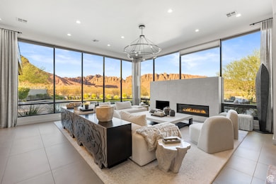 Living area featuring a mountain view, expansive windows, light tile patterned floors, a glass covered fireplace, and recessed lighting