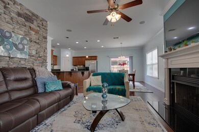 Living Room with lots of natural light, hardwood flooring throughout, fireplace, stone wall accent, surround Sound speakers built-in!