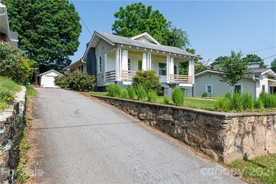 Level yard with covered front porch and rear detached garage for compact cars or storage, shared driveway