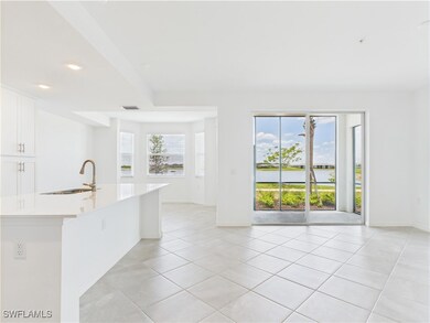 Kitchen featuring light countertops, light tile patterned floors, white cabinets, a center island with sink, and recessed lighting