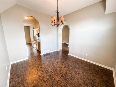 Empty room featuring arched walkways, a chandelier