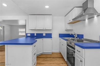 Kitchen featuring wall chimney exhaust hood, stain