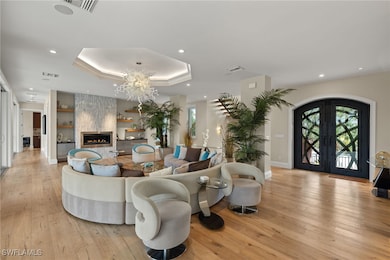 Living room with a tray ceiling, light hardwood /