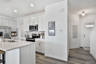 Kitchen featuring tasteful backsplash, stainless steel appliances, white cabinetry, light stone counters, and dark wood-style flooring