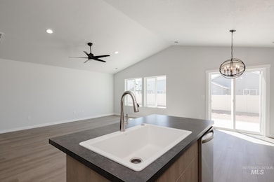 Kitchen featuring dark countertops, light wood-style floors, recessed lighting, open floor plan, and an island with sink