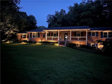 Single story home with a porch, a front lawn, and brick siding, landscape lighitng