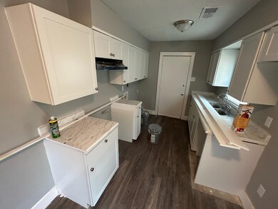 Kitchen with white cabinetry and dark hardwood / w