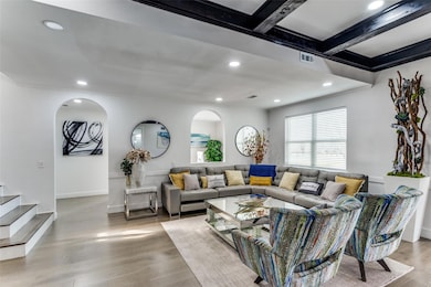 Living room featuring beamed ceiling, light hardwo