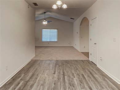 Empty room with arched walkways, a ceiling fan, lofted ceiling, and wood finished floors