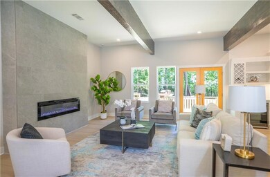 Living room with beam ceiling, wood finished floors, a tiled fireplace, recessed lighting, and baseboards