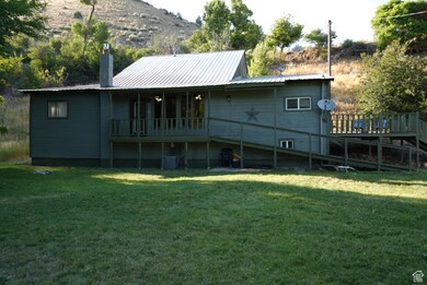 Back of property with a metal roof, a yard, a chimney, and a wooden deck
