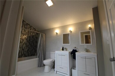 bathroom with dual vanities, tiled tub/shower and 