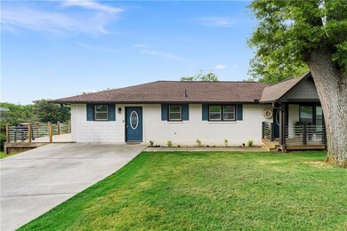 Single story home with a front yard, concrete driveway, brick siding, and a shingled roof