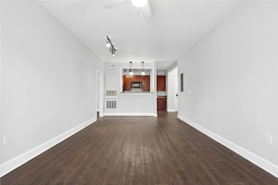 Unfurnished living room with dark wood-style floors, visible vents, and ceiling fan
