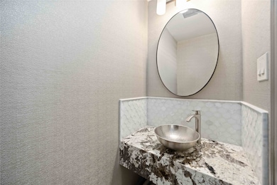 Stylish half bath with granite vanity, vessel sink, and designer tile accents - a sleek upgrade for guests.