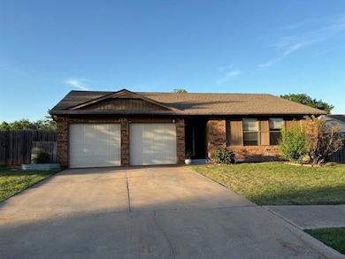 Ranch-style house with a garage, concrete driveway, roof with shingles, and brick siding