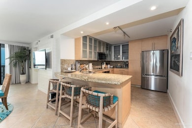 Kitchen with appliances with stainless steel finishes, light stone counters, a sink, baseboards, and glass insert cabinets