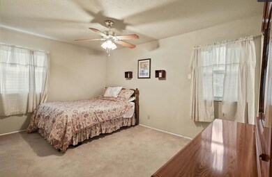 Bedroom with light carpet, ceiling fan, a textured