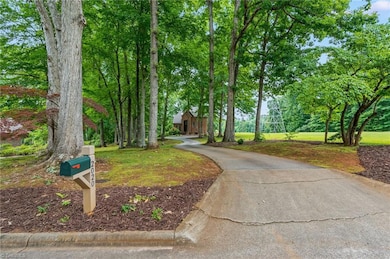 The winding driveway, flanked by mature hardwoods, offers a sense of peace and tranquility for this stately home.