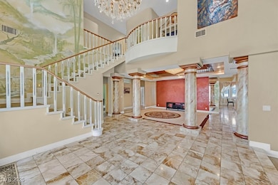 Foyer with decorative columns, stairs, a chandelier, and a towering ceiling