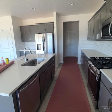 Kitchen featuring stainless steel appliances, light countertops, decorative backsplash, recessed lighting, and a center island with sink