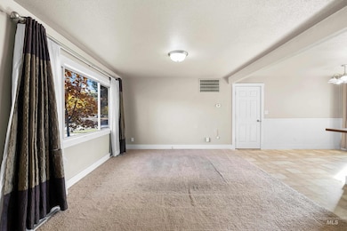 Spare room with a textured ceiling, light colored carpet, and wainscoting