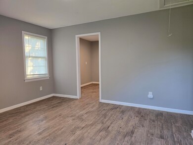 Unfurnished room with attic access, baseboards, an