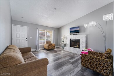 Living area featuring a brick fireplace, vaulted c