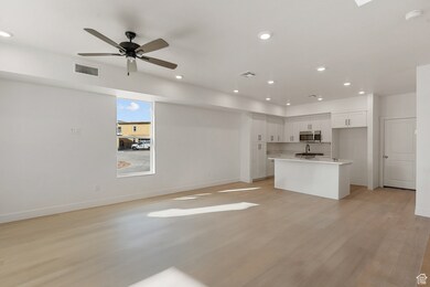 Kitchen with white cabinetry, open floor plan, recessed lighting, a kitchen island with sink, and light wood finished floors