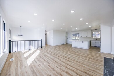 Kitchen with open floor plan, white cabinetry, recessed lighting, light wood-type flooring, and decorative light fixtures