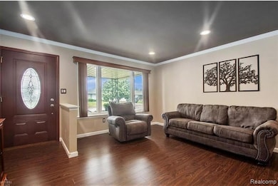 Living area with crown molding, dark wood-style flooring, and recessed lighting