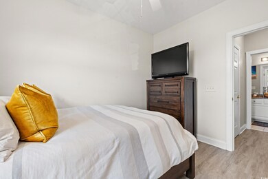 Bedroom with light wood-type flooring, connected b